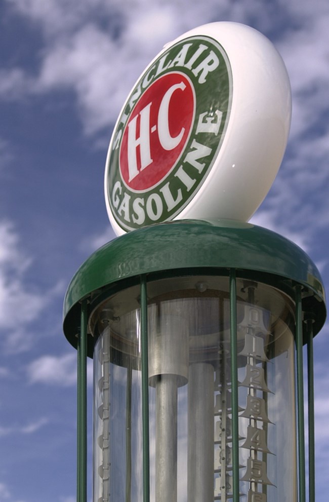 The green painted top of the restored gas pump has replacement glass and a Sinclair Gasoline H-C topper