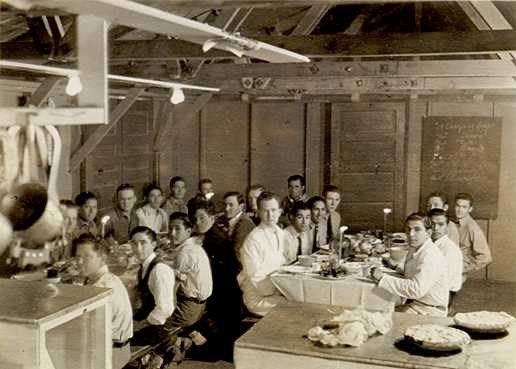black and white photograph of men sittting at tables about to eat dinner