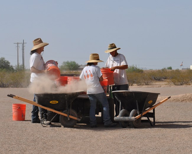 YCC and NACC students gathered around wheelbarrows of soil