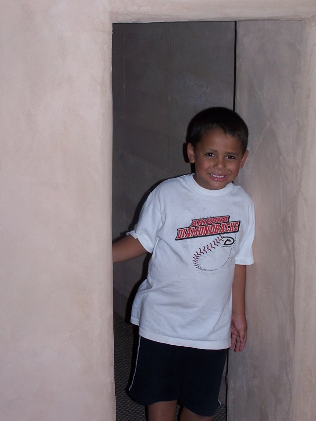 a young man enjoys walking through a small doorway similar to those of the Great House
