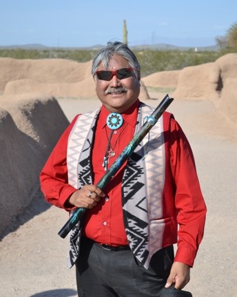 Loren Russell stands amongst the ruins at Casa Grande holding his flute