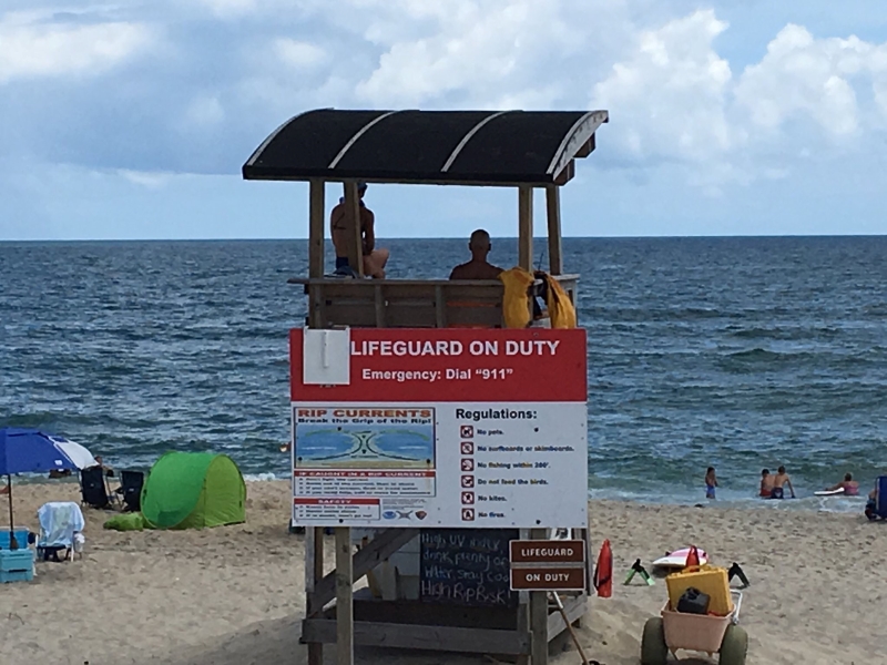Two lifeguards positioned on lifeguard stand looking toward Atlantic Ocean.