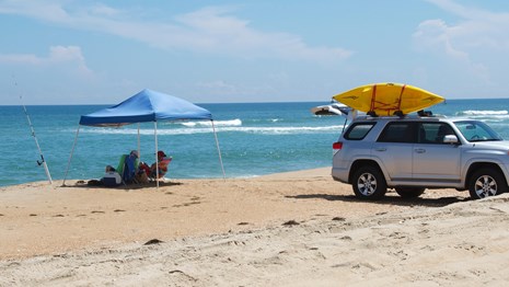 Family enjoying the beach with their off-road vehicle nearby.