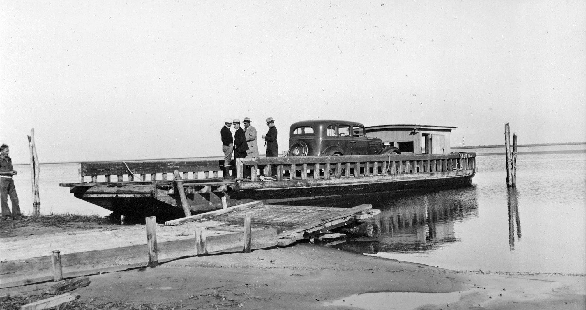 Yellowstone Superintendent Roger W. Toll led an NPS party to investigate the suitability of the Outer Banks as a national seashore in 1934. Toll took this photograph as the party prepared to cross Oregon Inlet. Yellowstone Superintendent Roger W. Toll and three other individuals on a vehicle ferry, 1934.