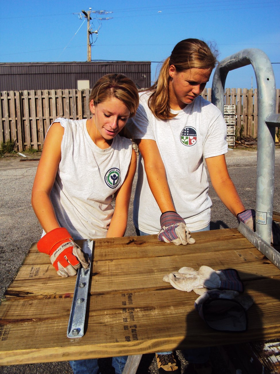 YCC crew members work on picnic table.