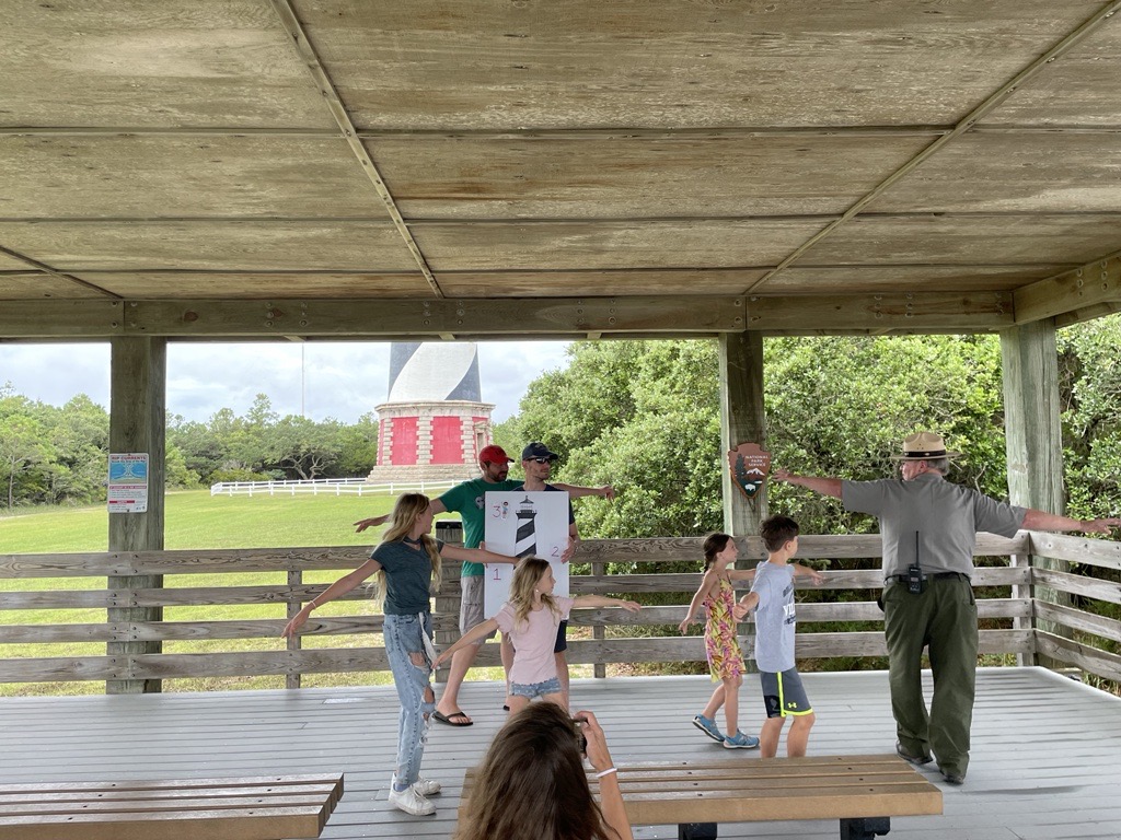 Ranger dancing with group of school children under pavillion.