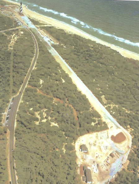 An aerial photograph shows the Cape Hatteras Lighthouse with a path cut through the trees to the lighthouse's new home.