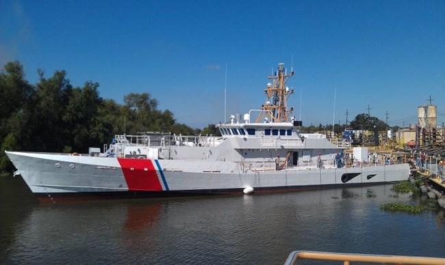 White USCG Cutter with thick orange and thin blue stripe on hull.