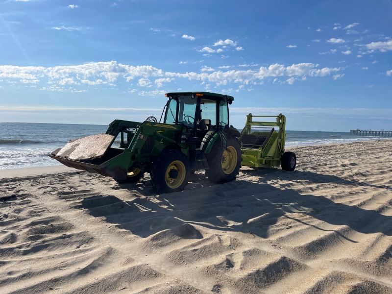 Cape Hatteras National Seashore's surf rake. Photo of a green tractor and surf rake on the beach on a sunny day.