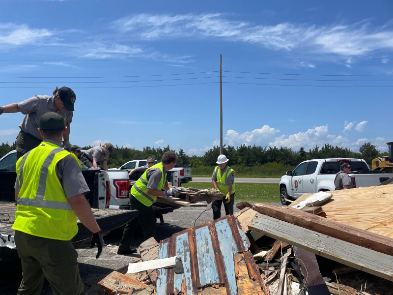 Photo of uniformed National Park Service employees unloading truckloads of debris.
