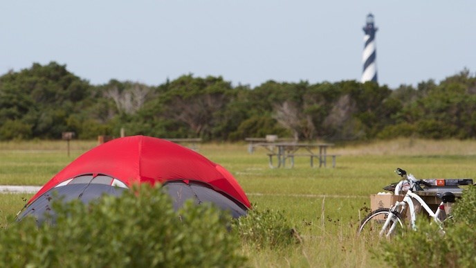 Tent with red cover at Cape Point Campground; Cape Hatteras Lighthouse in background