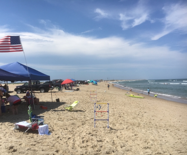 Visitors enjoying the beach near Cape Point with Cape Hatteras Lighthouse in the background.