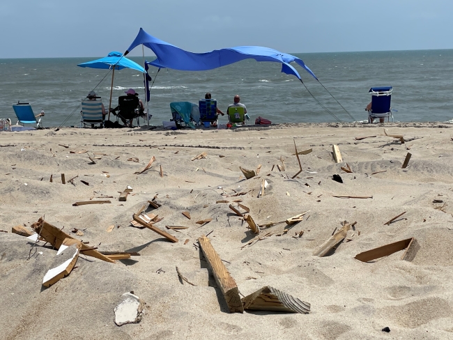 Small pieces of wooden debris on beach near beachgoers.