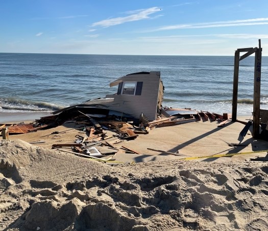 Remnants of a fallen house on the beach and near the ocean.