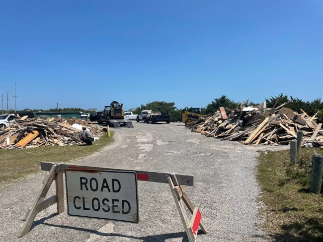 Debris staging area at ORV Ramp 23, located south of Salvo, N.C. "Road Closed" sign in front of large piles of collected beach debris.