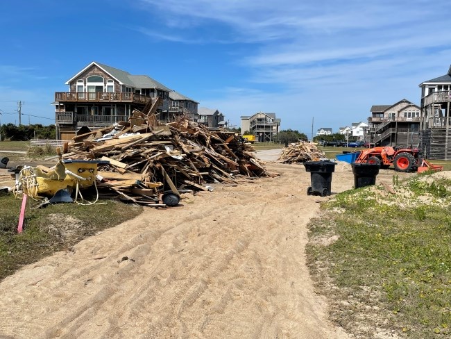 Large pile of house collapse debris near several houses.