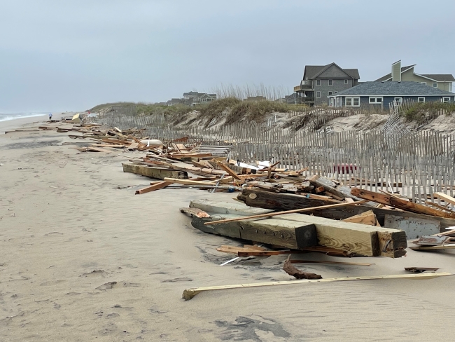 Piles of wooden debris washed ashore on beach.