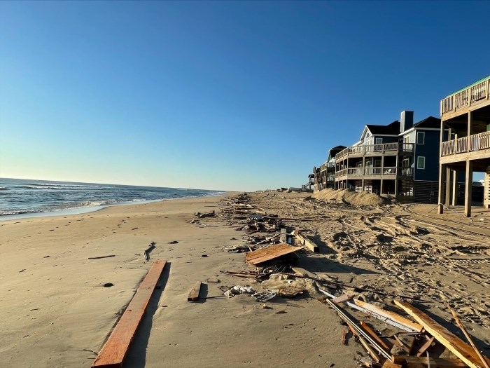 Debris from collapsed house stretching across length of beach.