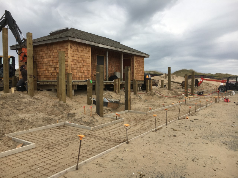Frisco Beach Access upgrade project work. Contractors and construction vehicles take part in a project to replace sidewalk, ramps, and exterior of restroom facility.