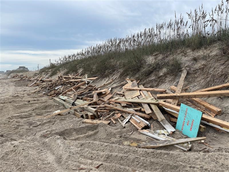 House collapse debris collected along the dune in Rodanthe 09-26-2024 Piles of house collapse debris lined up along a dune near beach.