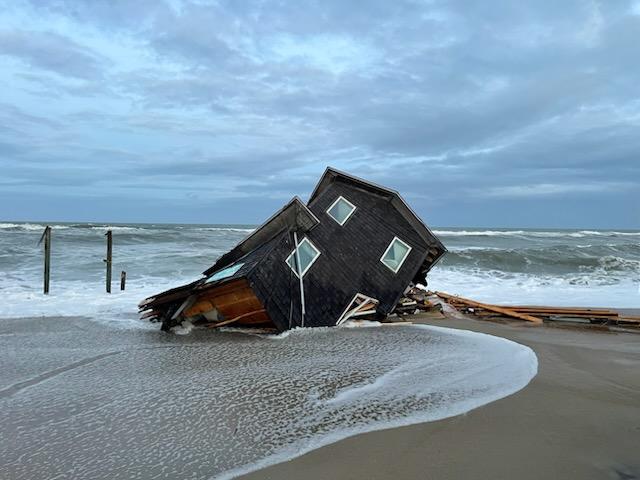 Photo of a collapsed house on the beach near the ocean.