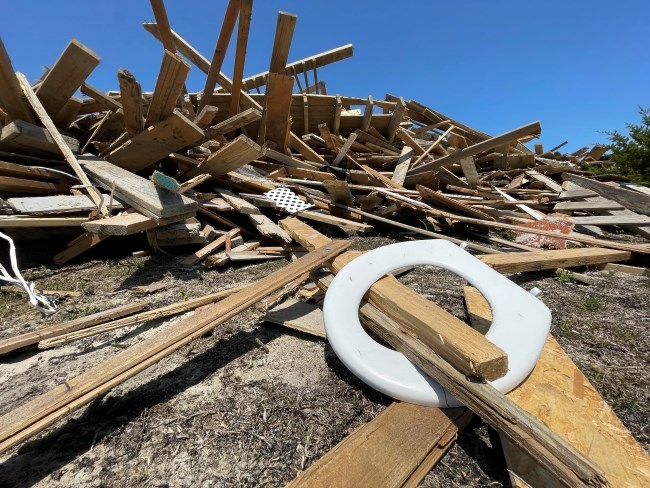 Large pile of collected beach debris, including a white toilet seat cover.