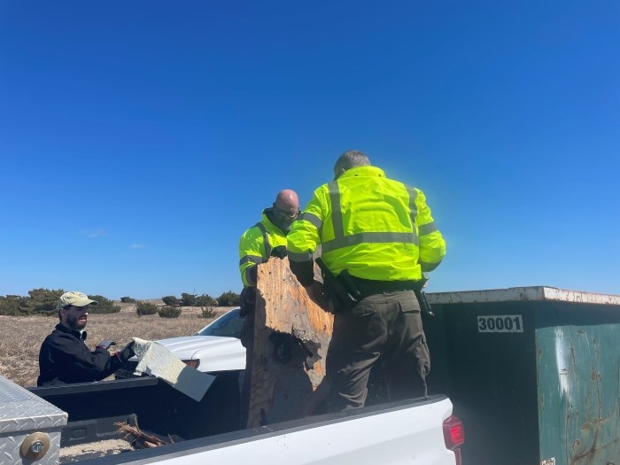 National Park Service staff transfer debris from a truck to a dumpster.