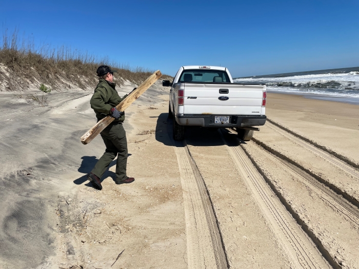 Photo showing NPS employee carrying debris to truck.