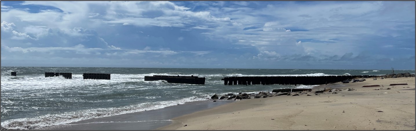 Image of a broken groin (or jetty) near the water.