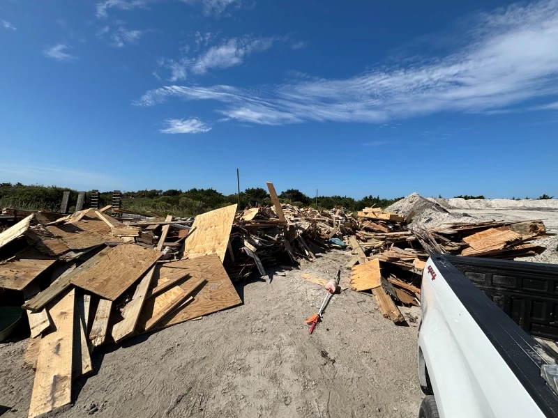 Staging area containing contractor and Cape Hatteras National Seashore employee collected house collapse debris. Photo of large piles of collected house collapse debris.