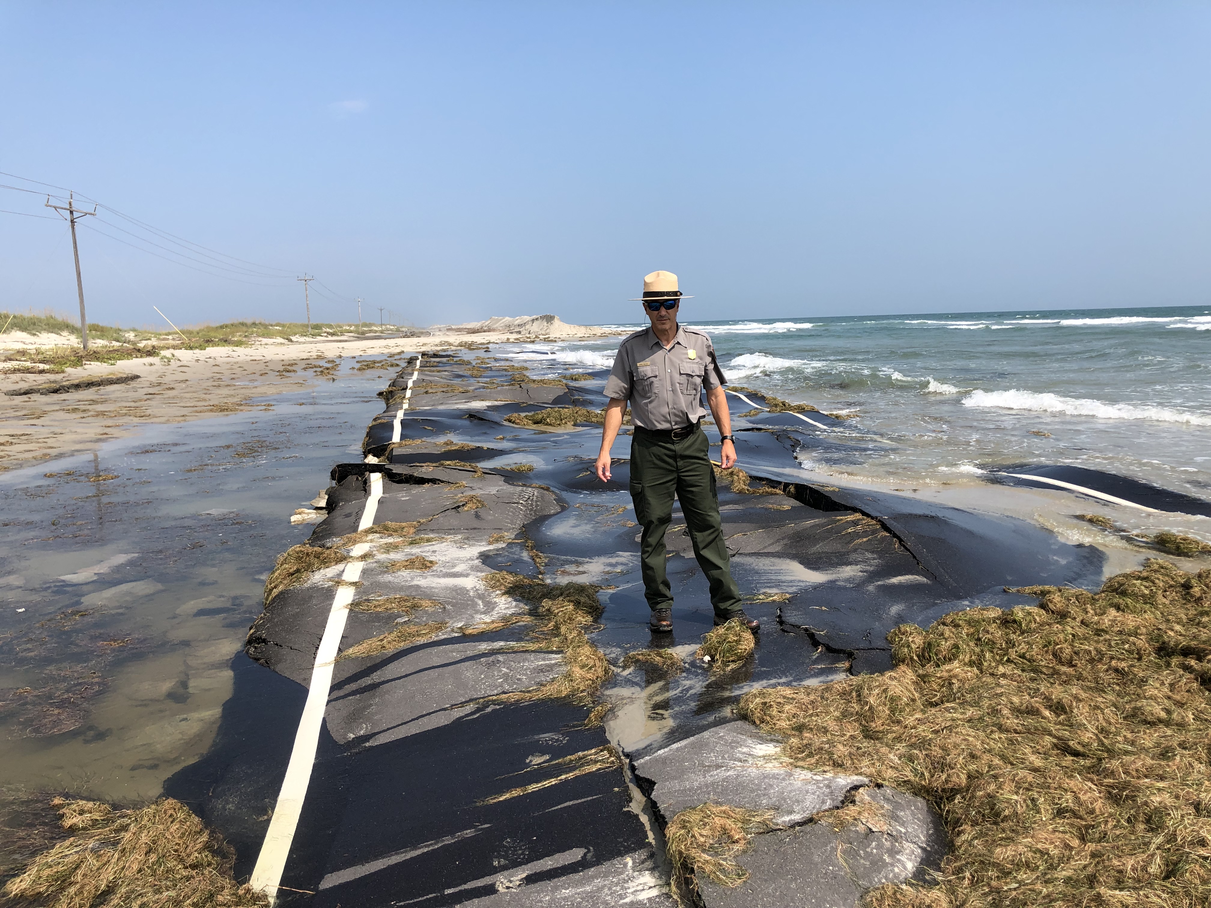 Superintendent David Hallac standing on a damaged stretch of NC-12 on Ocracoke Island.