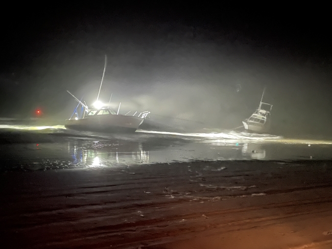 Two vessels grounded on beach at night in foggy conditions.