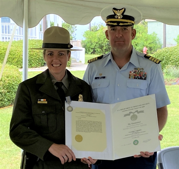 Valerie Streiff with Silver Lifesaving Medal. Park Ranger holds silver lifesaving medal certificate while standing next to Coast Guard officer.