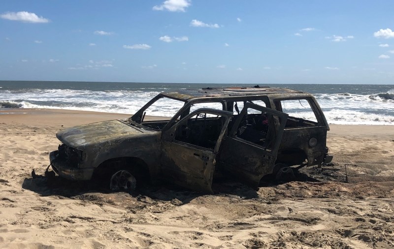 Photo of vehicle destroyed by fire on the beach.