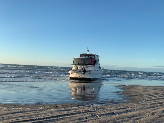 A white vessel sits grounded on beach.