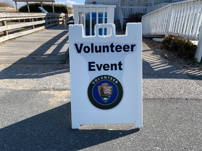 Volunteer event sign in Rodanthe, N.C. White sign that says "Volunteer Event" with volunteer/NPS arrowhead logo.