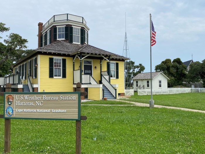 Photo showing sign that says U.S. Weather Bureau Station, Hatteras, NC, along with buildings and a metal tower.
