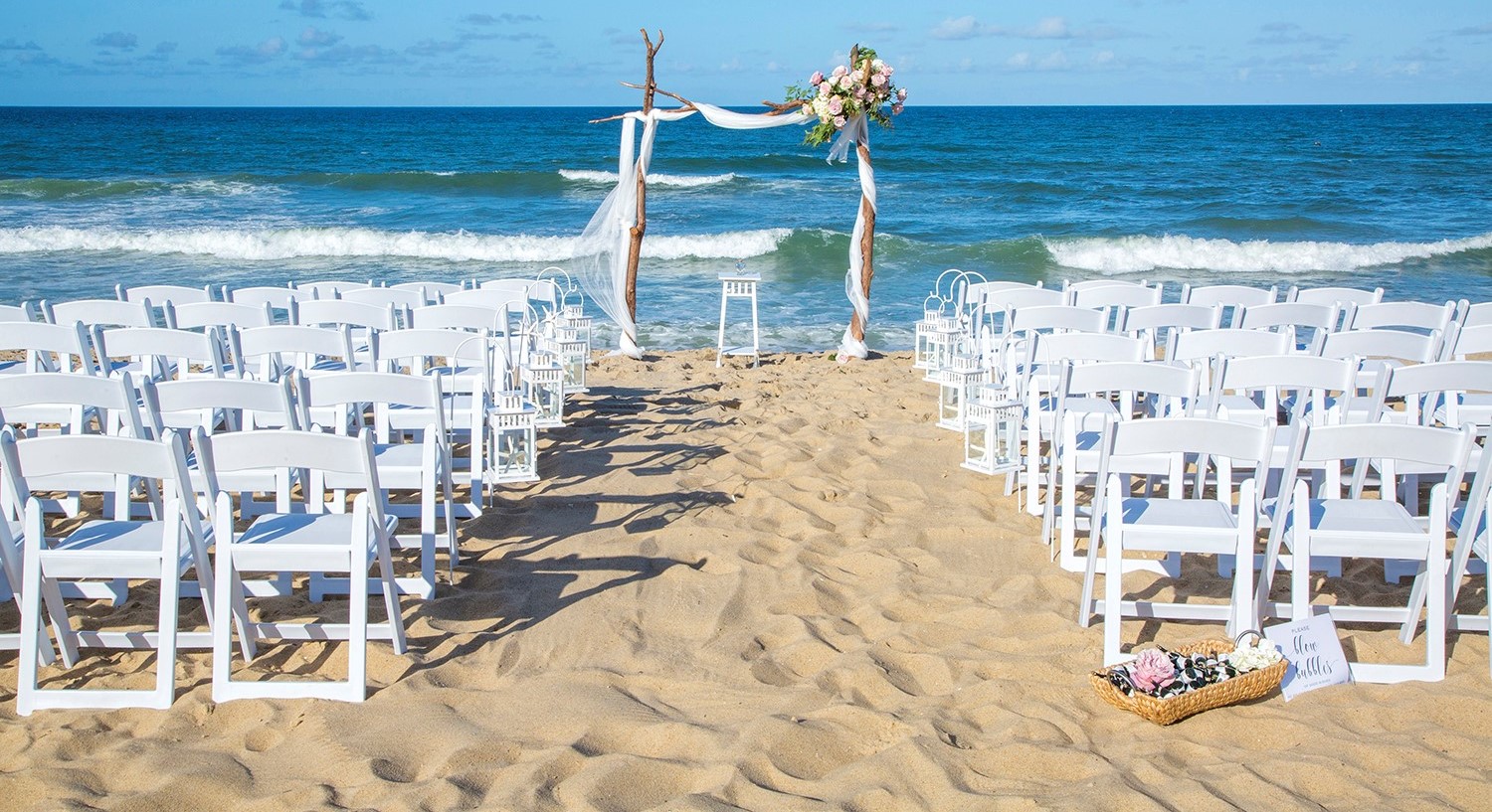 Beach wedding setup by a Cape Hatteras CUA holder. White chairs set up for a beach wedding in front of ocean.