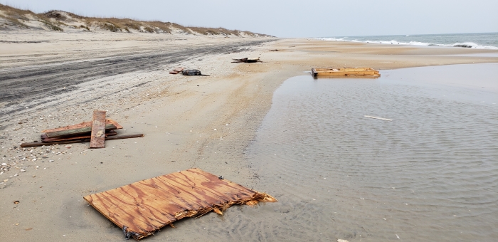 Various sized pieces of wood on beach from collapsed house.