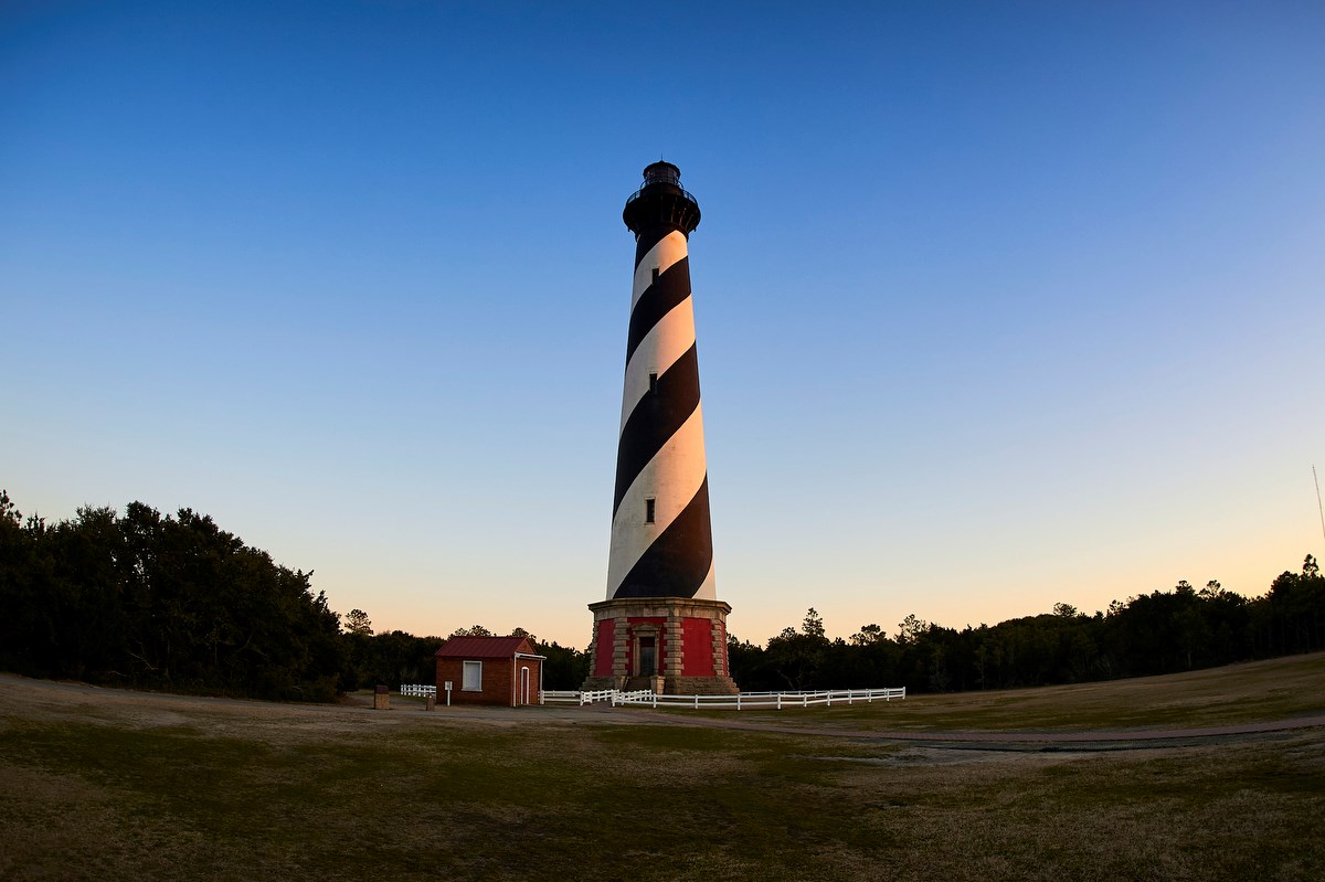 Cape Hatteras lighthouse. It is a brick lighthouse with a black and white spiral design against an evening sky.