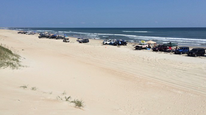 Visitors to the South Beach part of Cape Hatteras National Seashore with their off-road vehicles parked in a line along the beach.