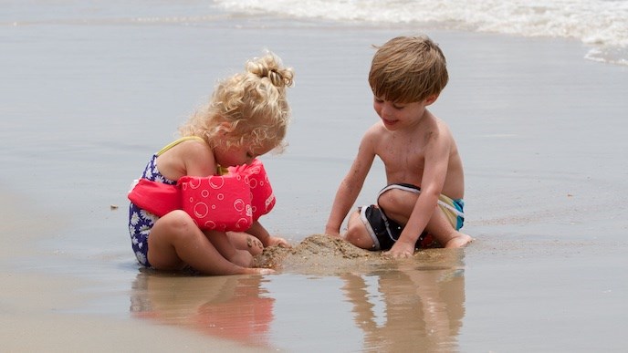 A young girl and boy playing in the sand and surf