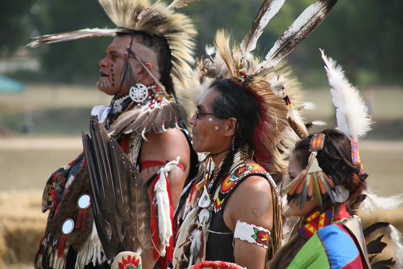 Dancers at a powwow wear regalia like feathers and face paint.