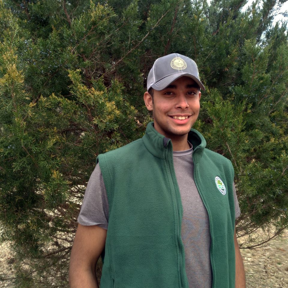 Portrait of Kalen Anderson standing in front of a shrub.