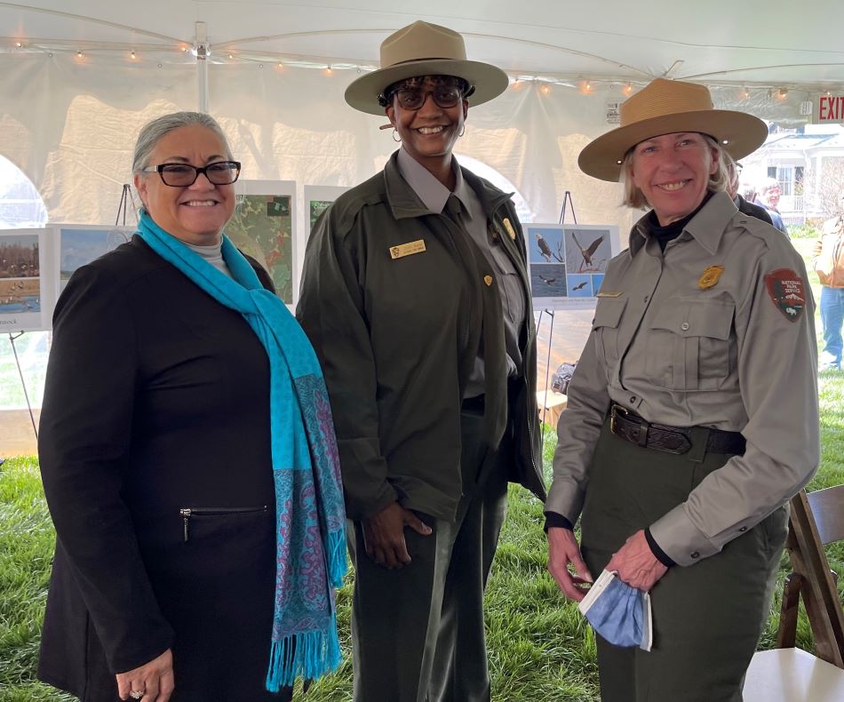 Group photo three women standing beneath a tent