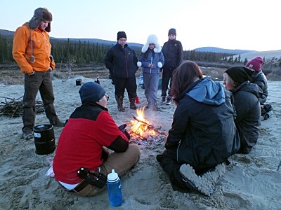 campers in warm clothes stand around a campfire campers in warm clothes stand around a campfire