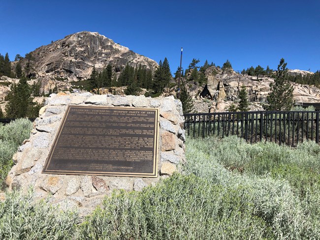 lt= . A low pedestal of local field stone embedded in concreate, with a large square plaque on top, tilted toward the viewer. The caption at the top of the plaque reads, “Stephens-Townsend-Murphy Party of 1844.”