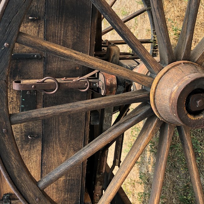 A wooden wagon wheel with spokes radiating out from a central point.