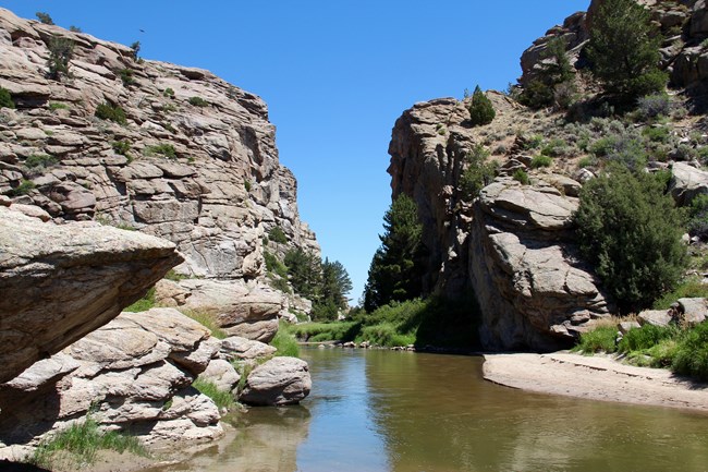 A river squeezes through a narrow passage between two sheer rock walls.