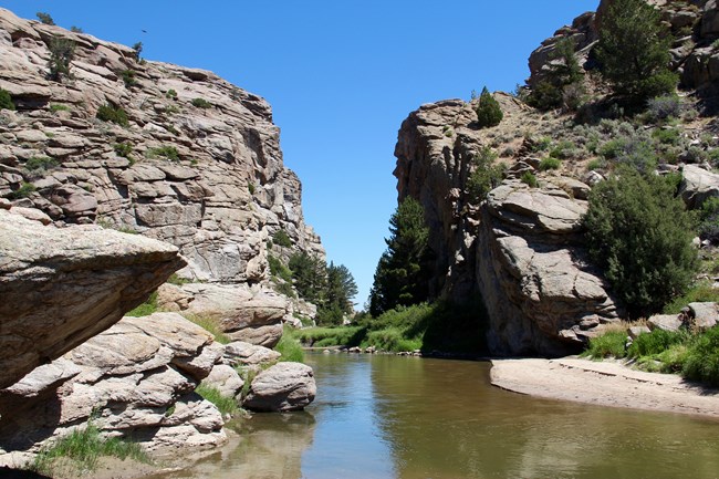 A river squeezes through a narrow passage between two sheer rock walls.